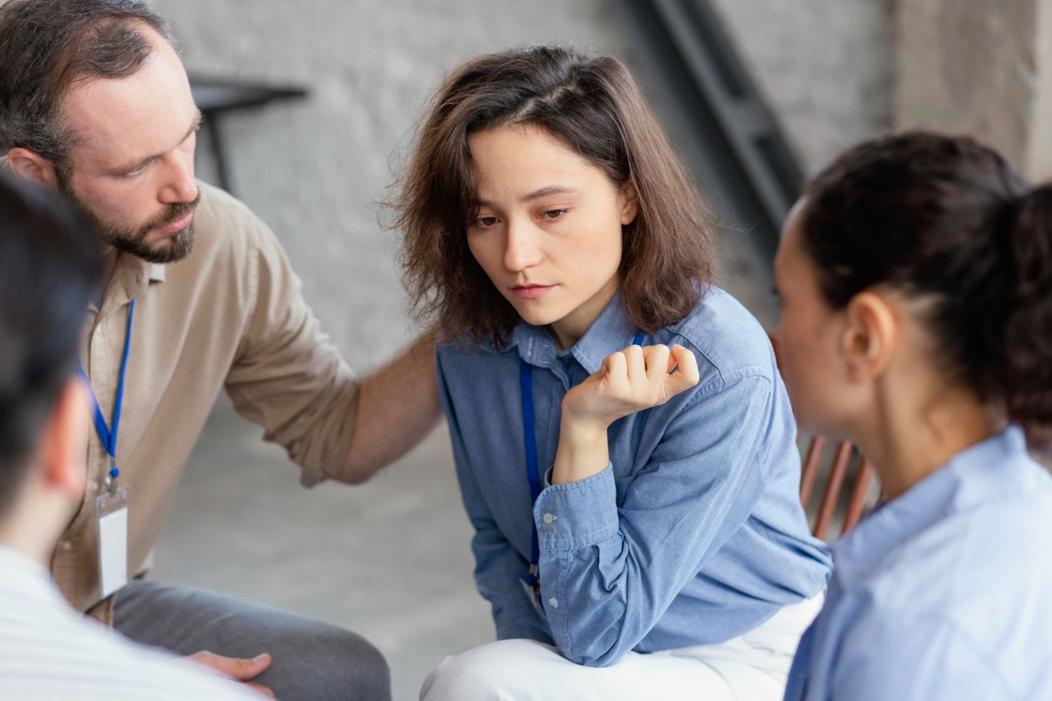 A woman in a blue shirt looks down while in a group, a person comforts her. Tennessee Vulnerable Persons Abuse Registry Law Attorney in Nashville, Tennessee