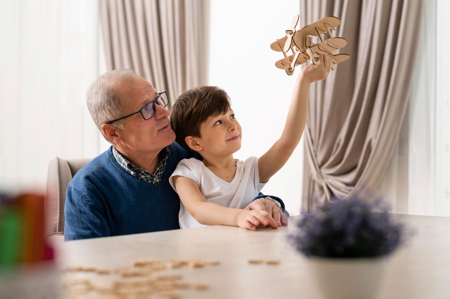 Grandfather and child play with a wooden airplane, sitting at a table in a bright room. Grandparent’s Rights Law Attorney in Nashville, Tennessee