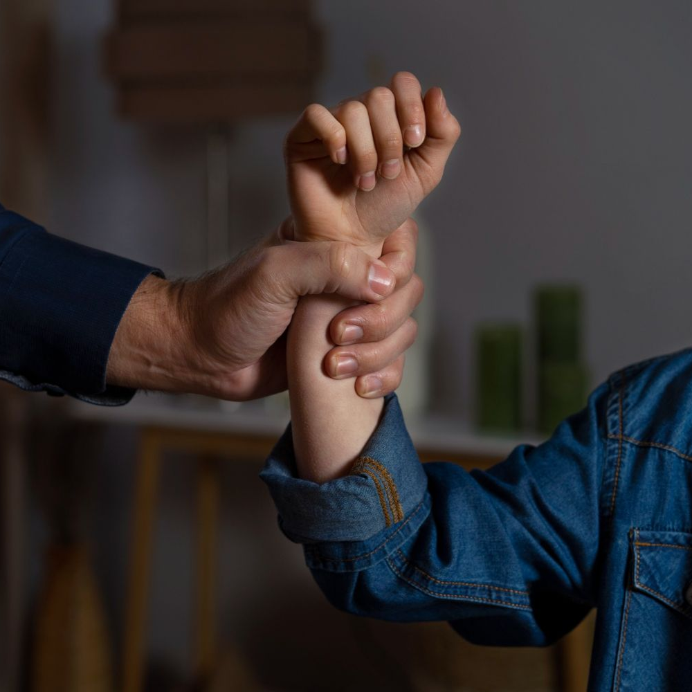 Adult hand gripping a child's arm. The child wears a denim jacket indoors. Domestic Assault Law Attorney in Nashville, Tennessee