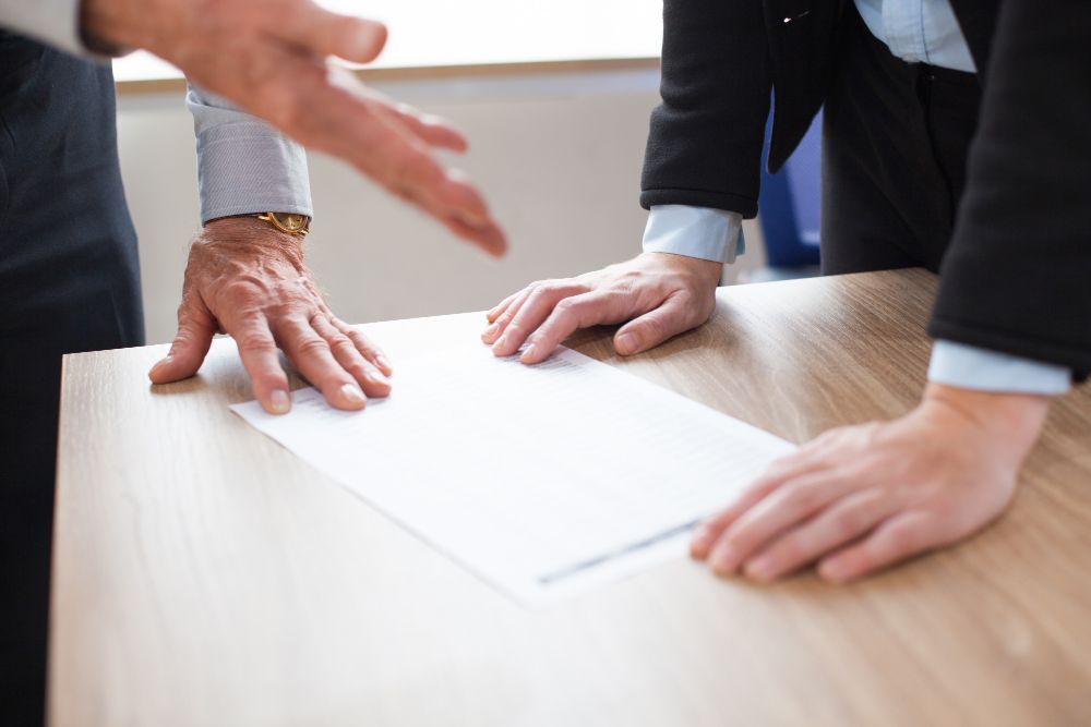 Two people examining a document on a wooden table, one gesturing with their hand. Boundary Disputes Law Attorney in Nashville, Tennessee