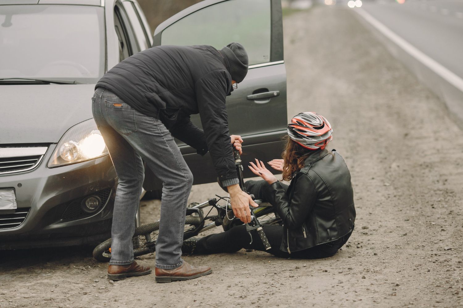 Man helping injured cyclist on roadside after an accident. Vehicular Assault Law Attorney in Nashville, Tennessee