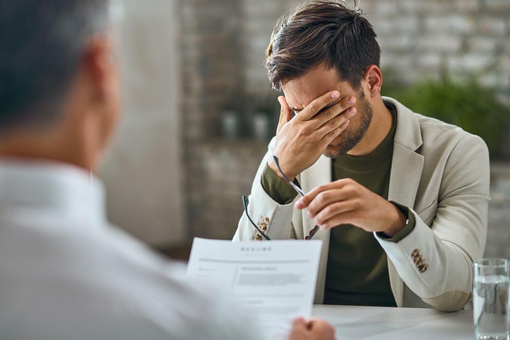 Man with head in hands, looking stressed during an interview. Breach of Contract Law Attorney in Nashville, Tennessee