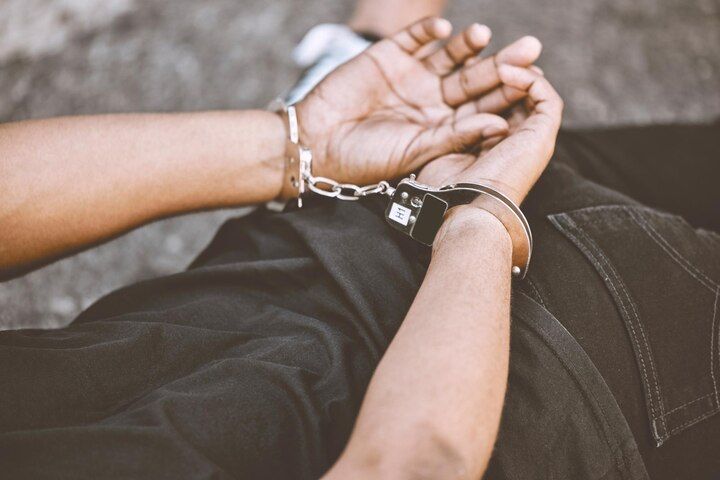 Person's wrists handcuffed, lying on a surface, wearing a black shirt and jeans. Resisting Arrest Law Attorney in Nashville, Tennessee