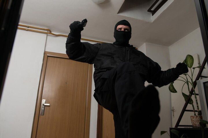 Person in black tactical gear, ski mask, and gloves points a gun indoors. Criminal Trespass Law Attorney in Nashville, Tennessee