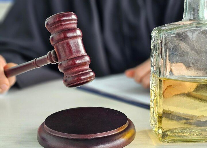 Judge with gavel and alcohol bottle on table. Public Intoxication Law Attorney in Nashville, Tennessee