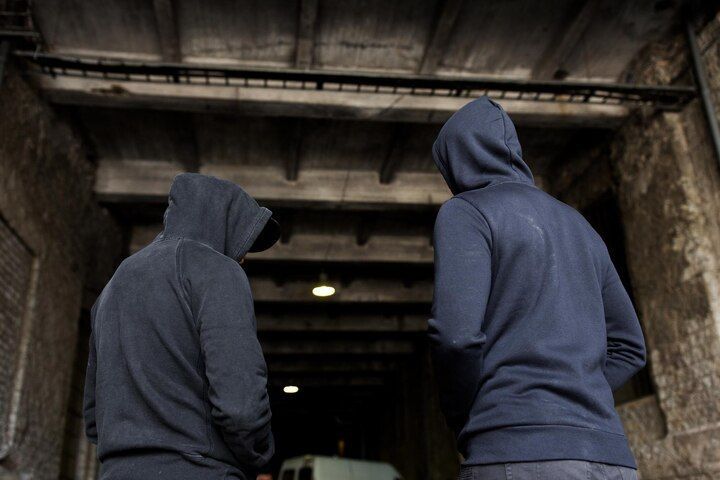 Two people in dark hoodies stand under an archway, backs to the camera, looking into a dim space. Aggravated Criminal Trespass Law Attorney in Nashville, Tennessee