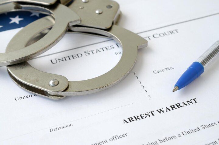Handcuffs on top of an arrest warrant form with a pen. OP Violations Law Attorney in Nashville, Tennessee