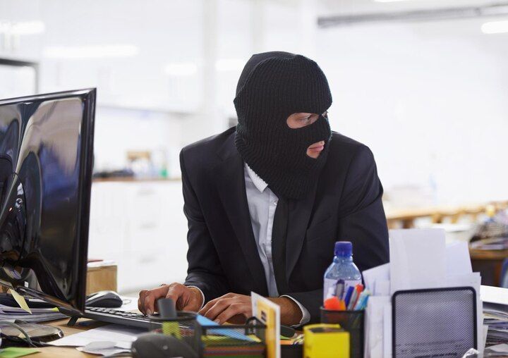 Person in black mask, suit, at a computer, looking to the side. Theft of Services Law Attorney in Nashville, Tennessee