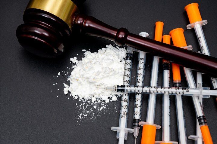 Gavel, pile of white powder, and syringes on a dark surface, possibly evidence. Possession With Intent Law Attorney in Nashville, Tennessee