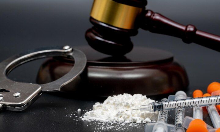 Handcuffs, gavel, white powder, syringes, and pills on a dark surface, symbolizing law enforcement and drug-related crime. Possession With Intent Law Attorney in Nashville, Tennessee
