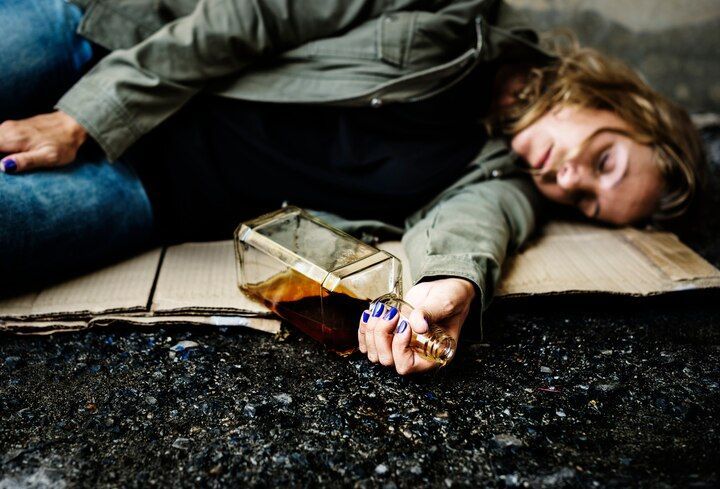 Woman on cardboard with empty liquor bottle. Asphalt setting. Public Intoxication Law Attorney in Nashville, Tennessee