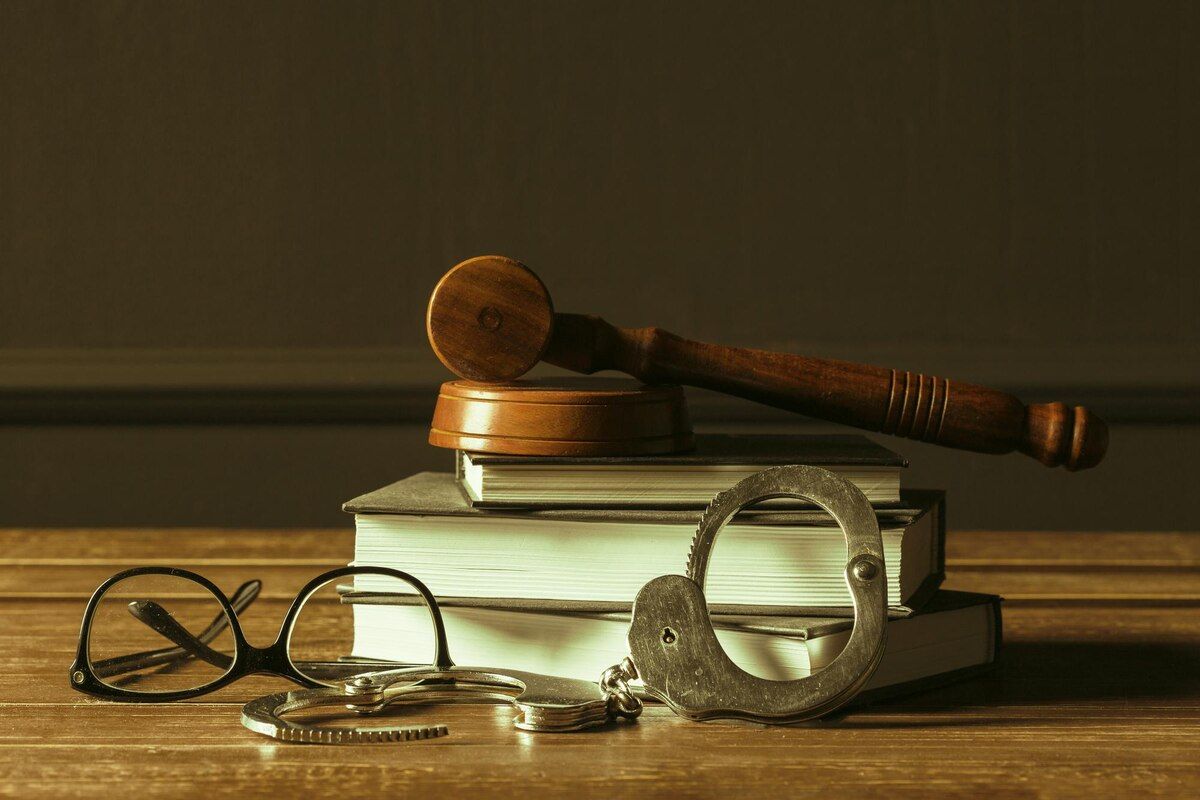Gavel on a stack of books with handcuffs and eyeglasses on a wooden surface. Criminal Impersonation Law Attorney in Nashville, Tennessee