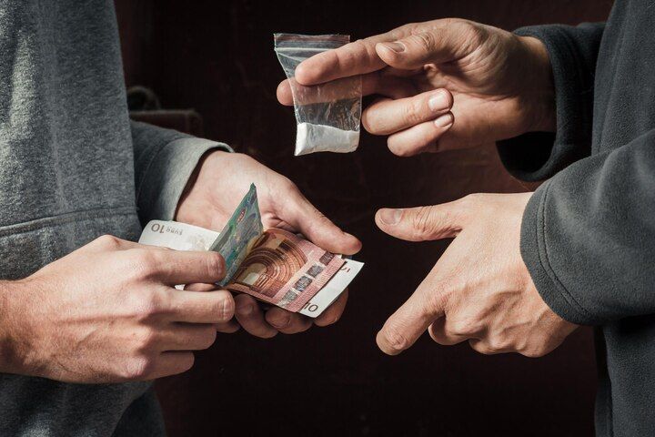 Two people exchanging cash for a bag of white powder, likely a drug deal. Drug Sale & Delivery Law Attorney in Nashville, Tennessee