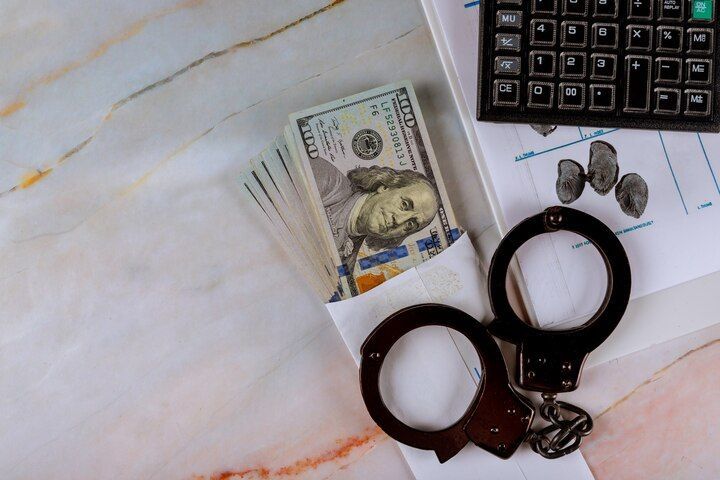 Handcuffs, money, calculator, and papers on a marble surface, suggesting financial crime. Embezzlement Charges Law Attorney in Nashville, Tennessee