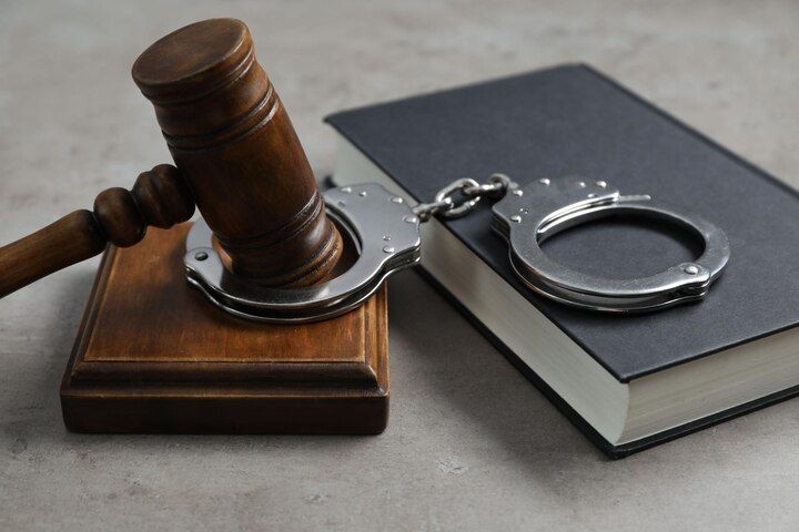 Wooden gavel and handcuffs rest on a closed book, symbolizing law and order. Criminal Impersonation Law Attorney in Nashville, Tennessee