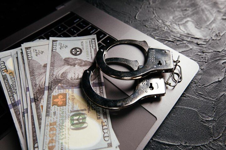 Handcuffs and cash on a laptop, suggesting a crime or financial investigation. Embezzlement Charges Law Attorney in Nashville, Tennessee