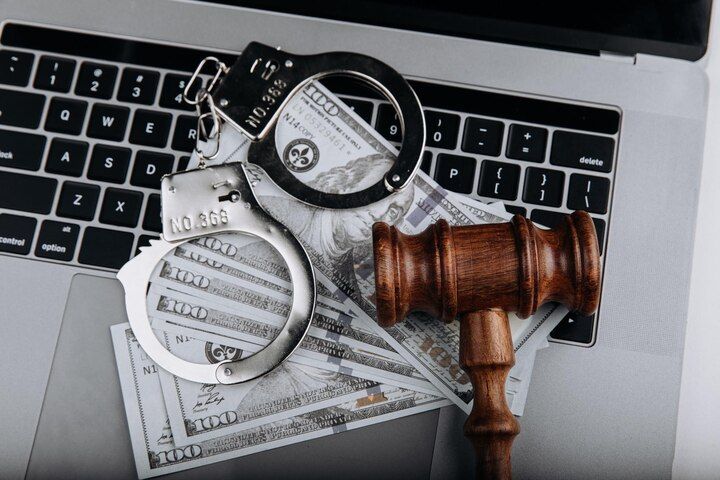 Handcuffs, cash, and gavel on a laptop keyboard, suggesting cybercrime and legal issues. Fraud Law Attorney in Nashville, Tennessee
