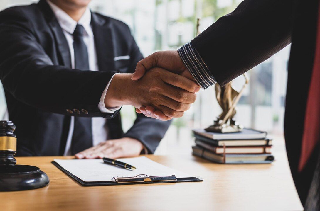Two people in suits shaking hands at a desk, papers and a gavel nearby. Fraud Law Attorney in Nashville, Tennessee