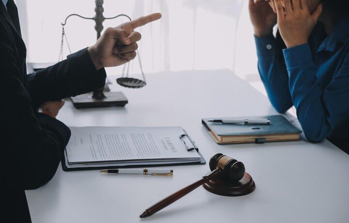 Lawyer points at document. Person with head in hands at a table, gavel, and scales of justice. Disorderly Conduct Law Attorney in Nashville, Tennessee