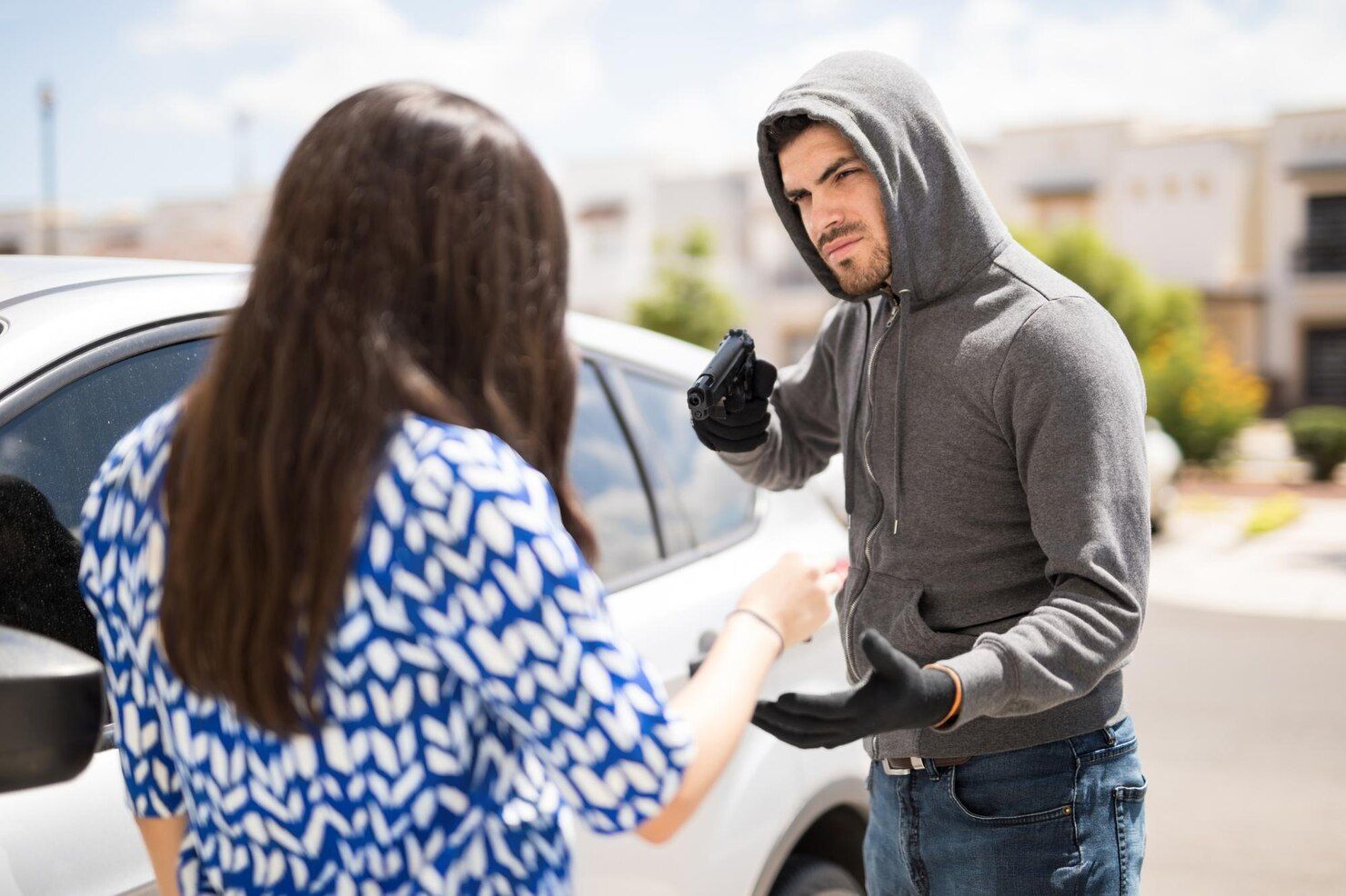 A person in a hoodie threatens a person next to a car, demanding keys. Aggravated Robbery Law Attorney in Nashville Tennessee