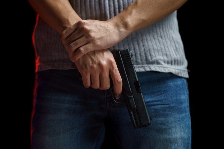 Person holding a handgun in front, against a black background. Firearm During Dangerous Felony Law Attorney in Nashville, Tennessee