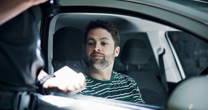 Man in car being handed document by police officer. Driving on Suspended License Law Attorney in Nashville, Tennessee