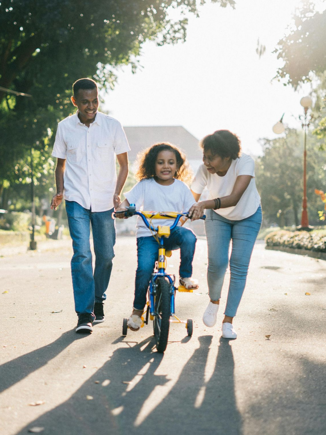 Family helps a child ride a bicycle on a sunny path. Family Law Practice Areas in Nashville, Tennessee