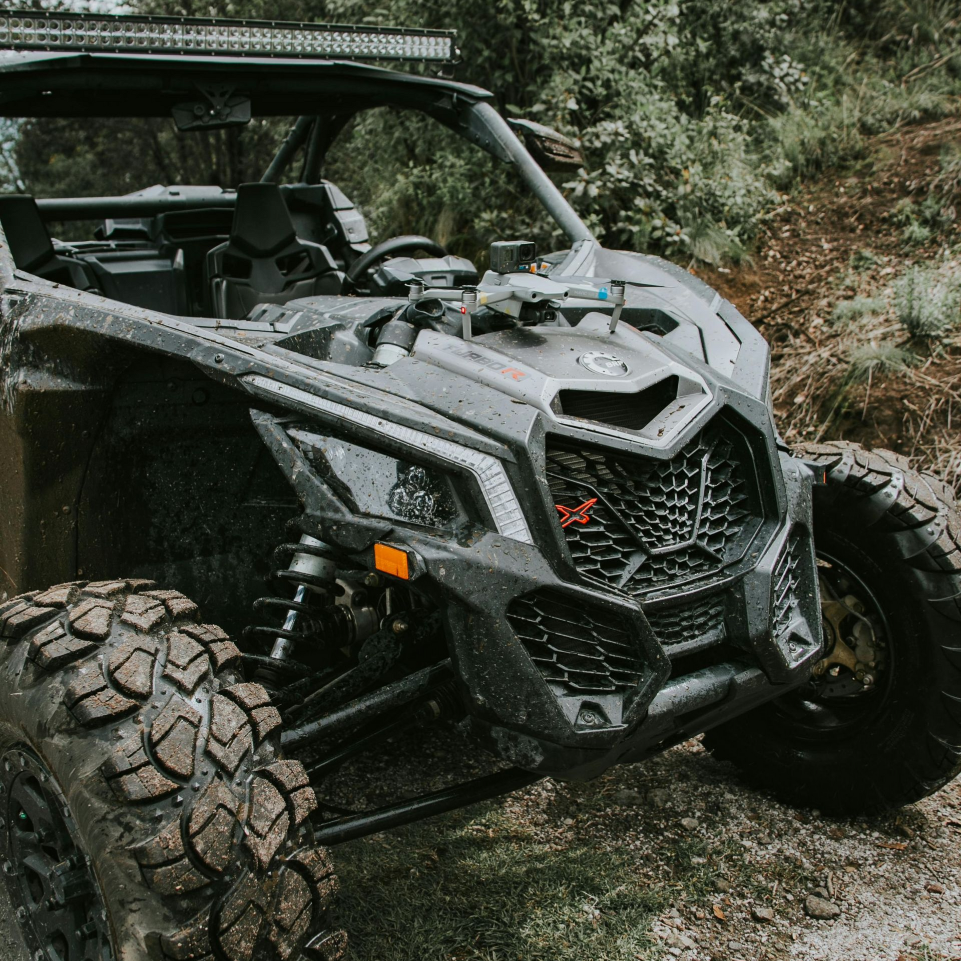 Black off-road vehicle with mud-covered tires parked on a dirt path in a wooded area. ATVAccidents Law Attorney in Nashville, Tennessee