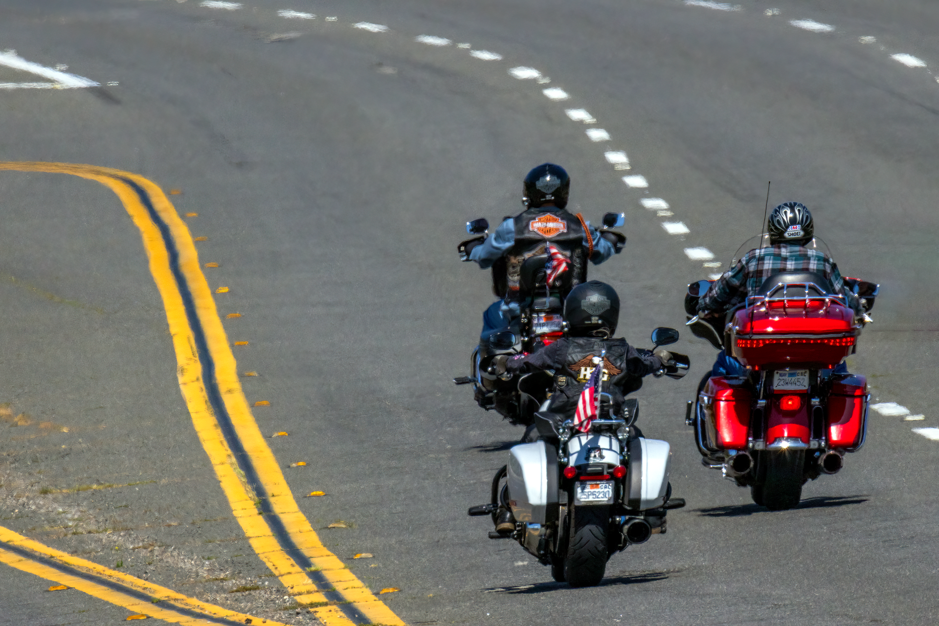 Three friends riding motorcycles together down an open road