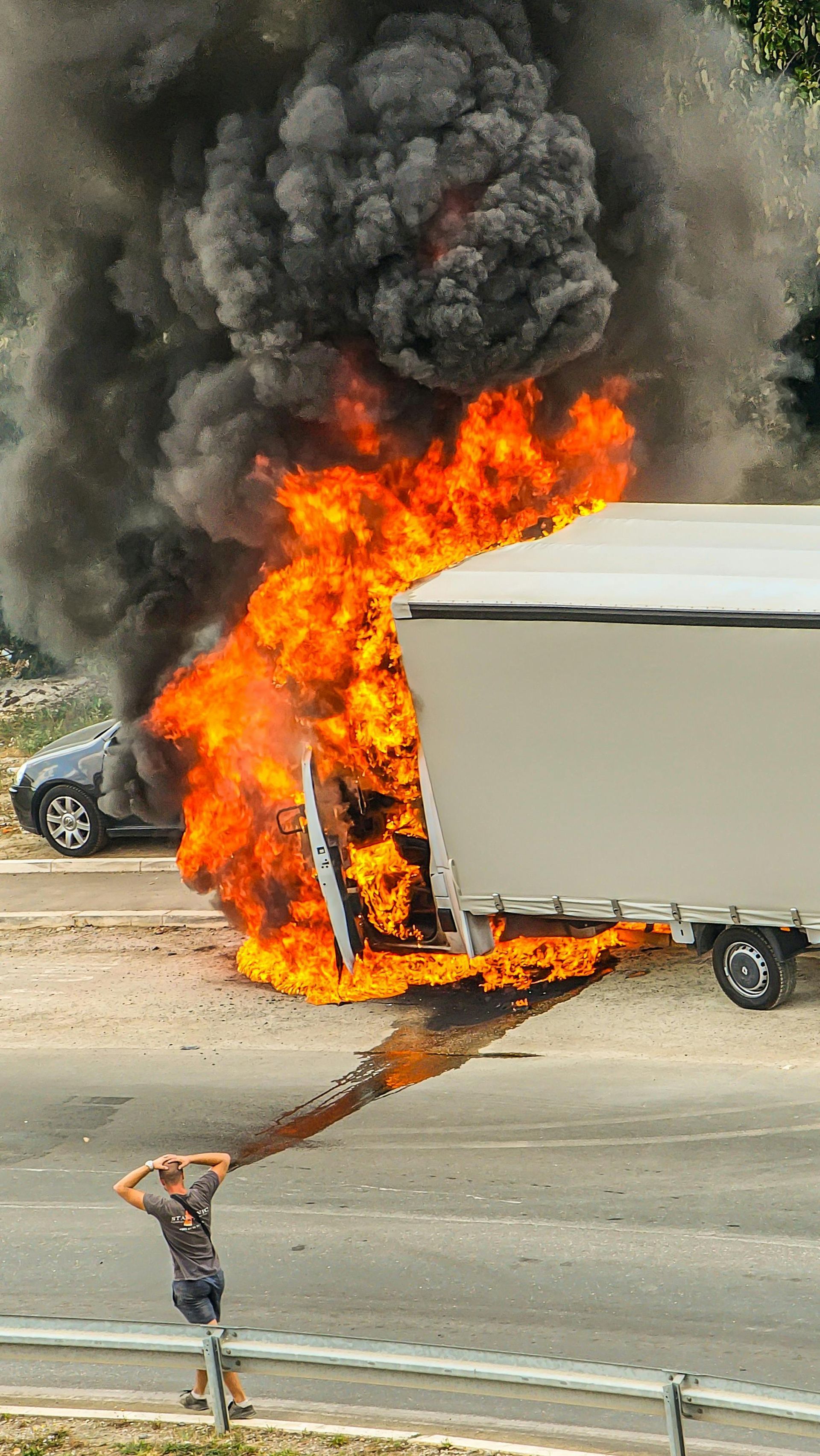 A truck and car on fire, billowing black smoke. A person stands nearby, watching the blaze. Truck Accidents Law Attorney in Nashville Tennessee