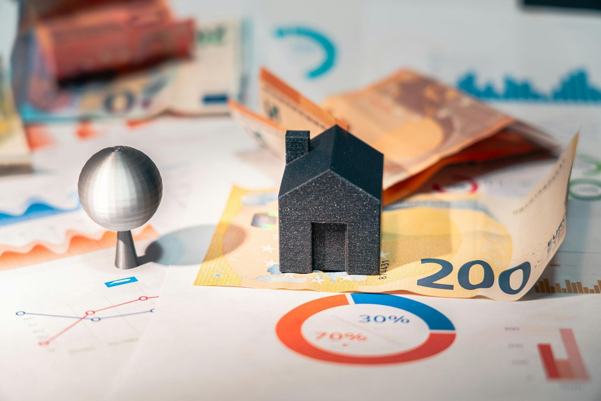 Small house and metal orb on money and graphs, suggesting real estate investment. Property and Cash Seizures (DEA and Local) Law Attorney in Nashville, Tennessee