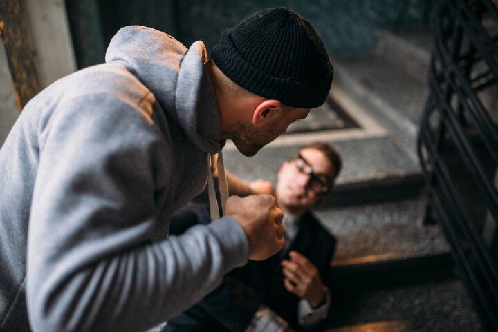 Man in gray hoodie confronting another man on stairs; fists raised. Crimes Against the Person Law Attorney in Nashville, Tennessee