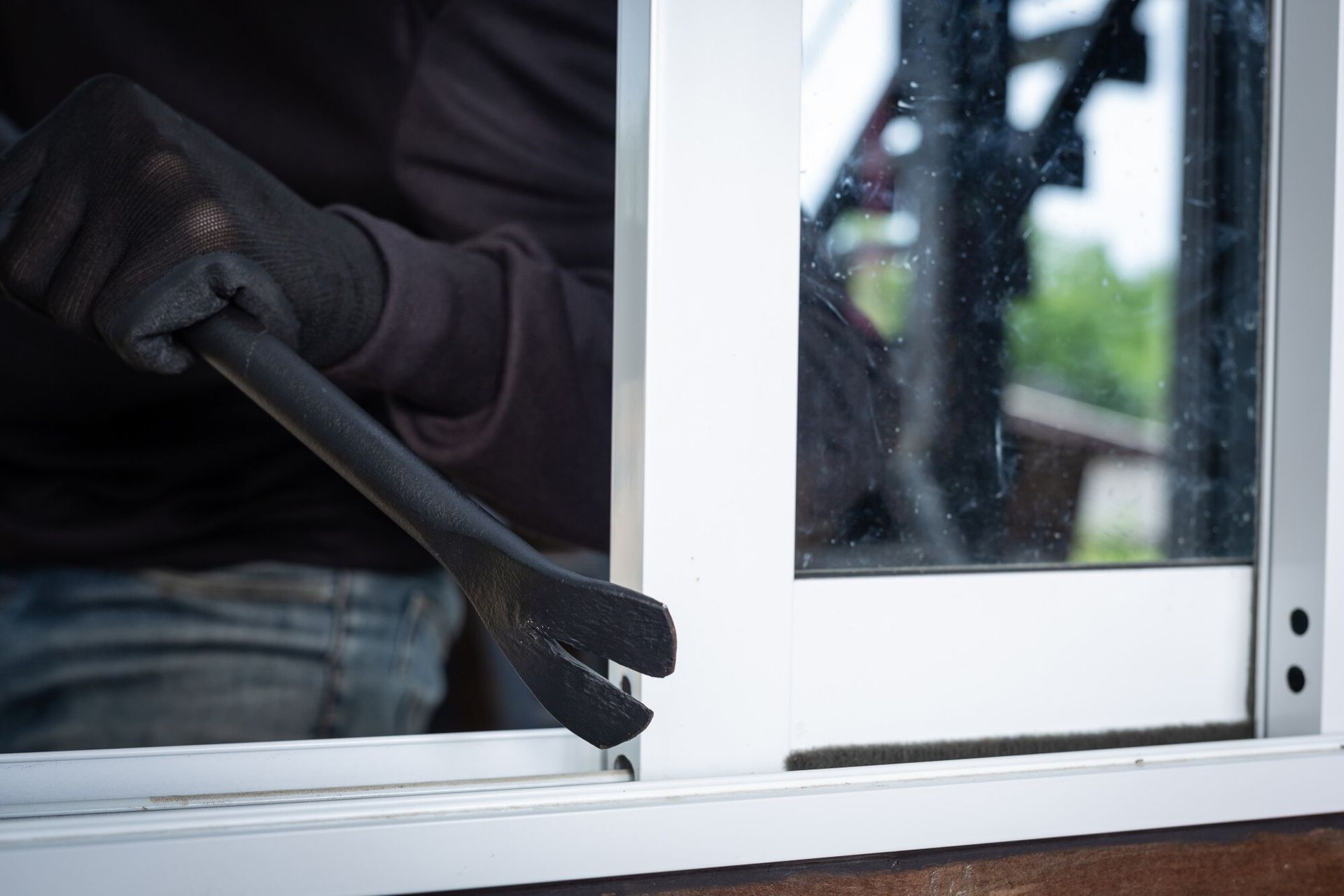 Person wearing gloves using a crowbar to pry open a window. Aggravated Burglary Law Attorney in Nashville Tennessee