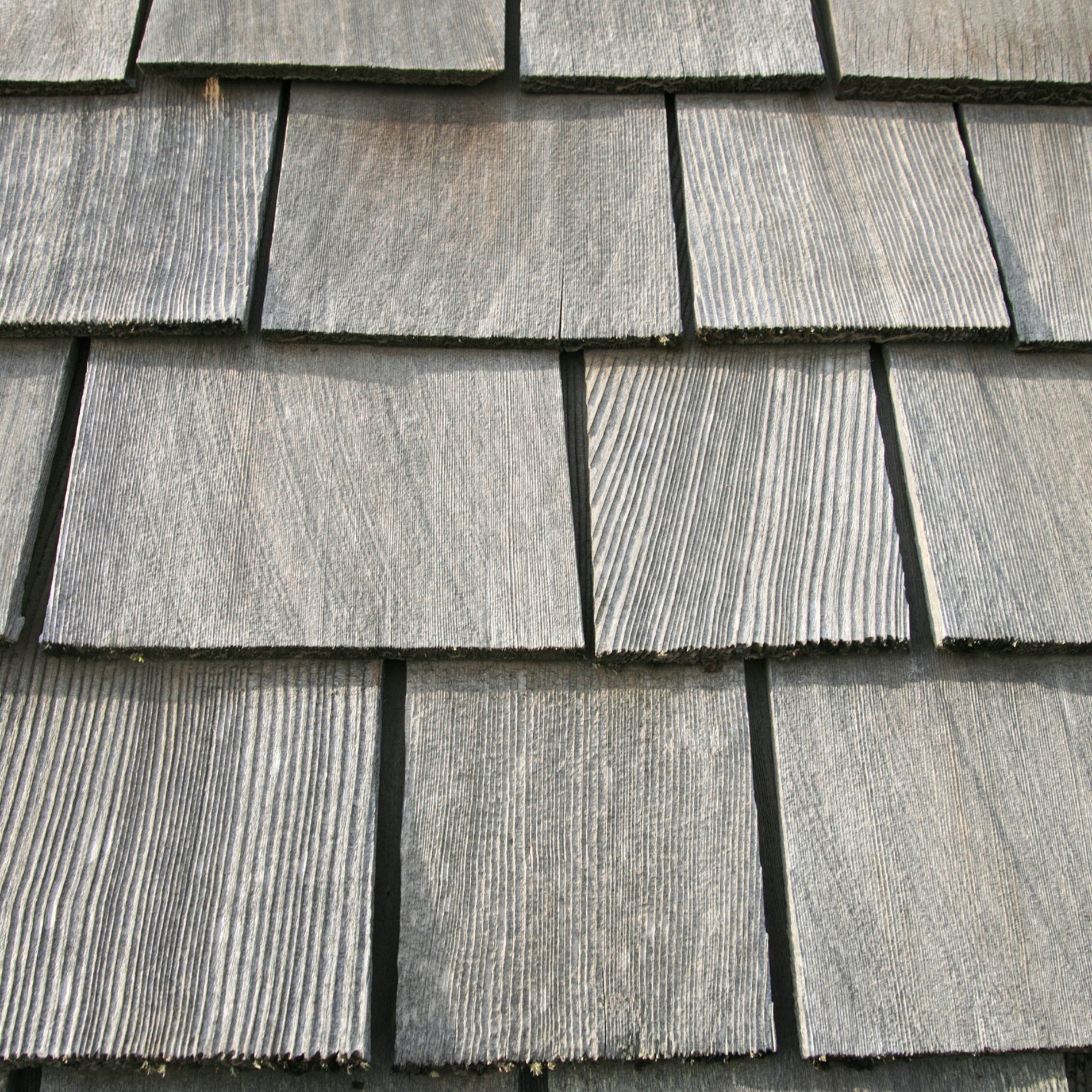 Close-up view of weathered gray wood shingles on a roof.