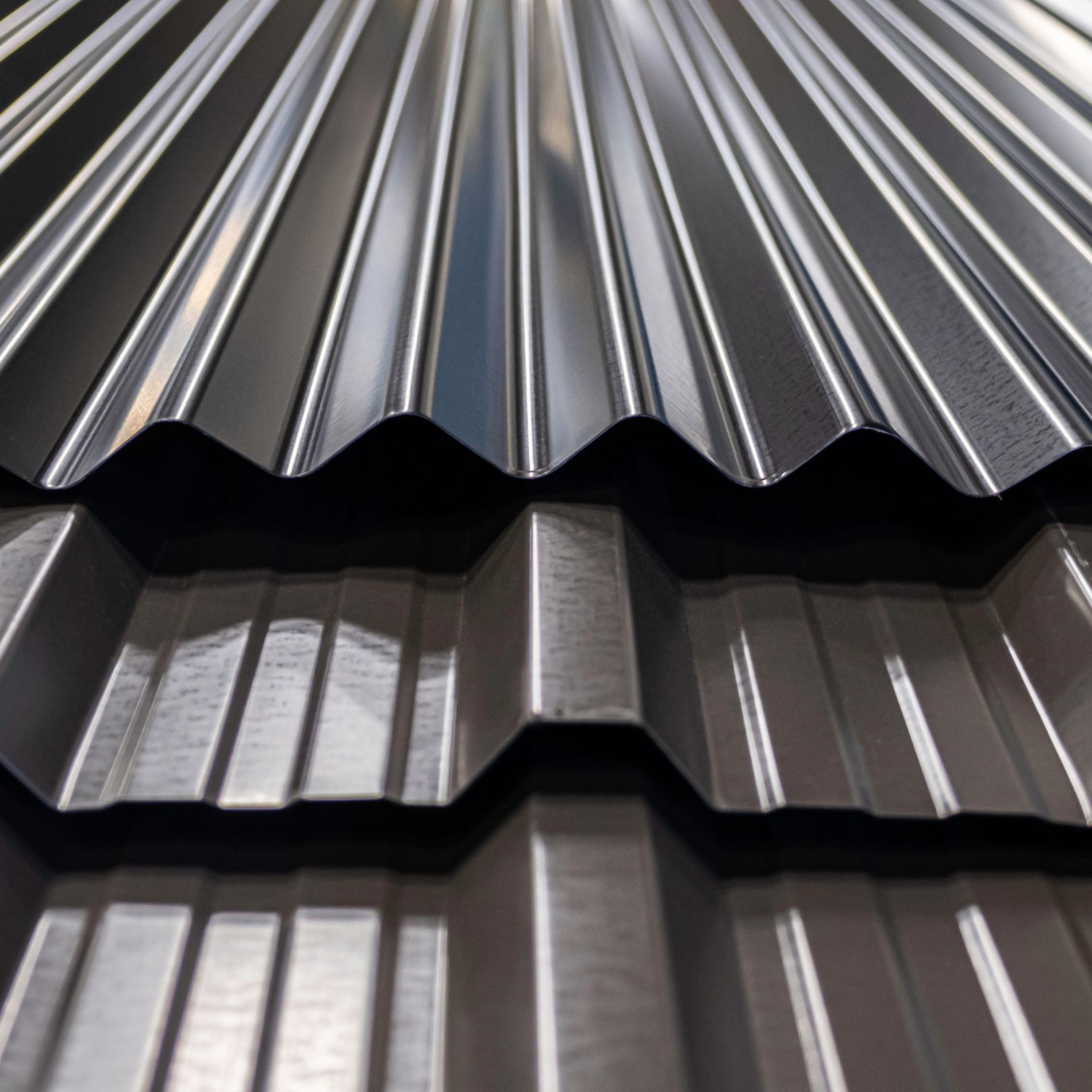 Close-up of overlapping corrugated metal roofing panels in shades of brown and black.