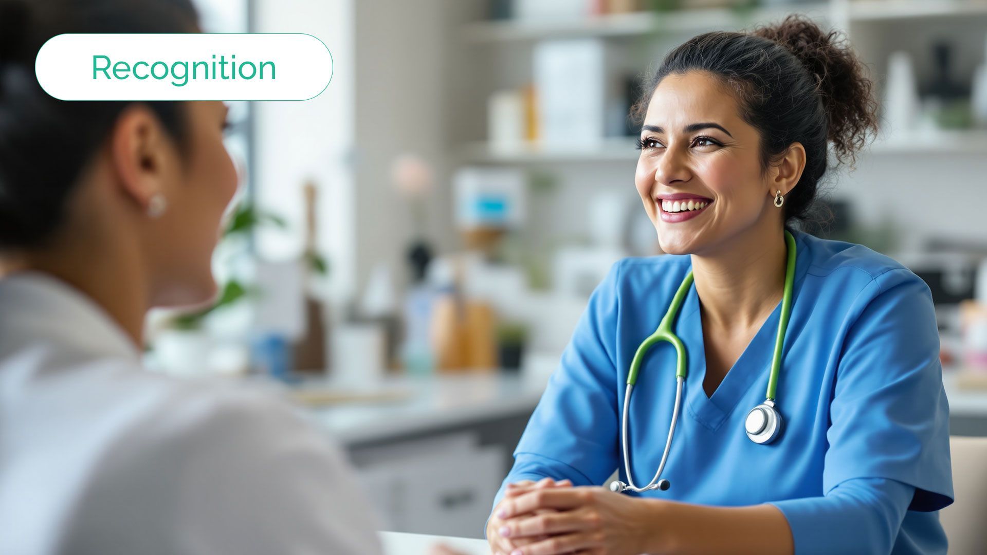 Smiling healthcare provider with stethoscope, speaking to a patient in an office setting.
