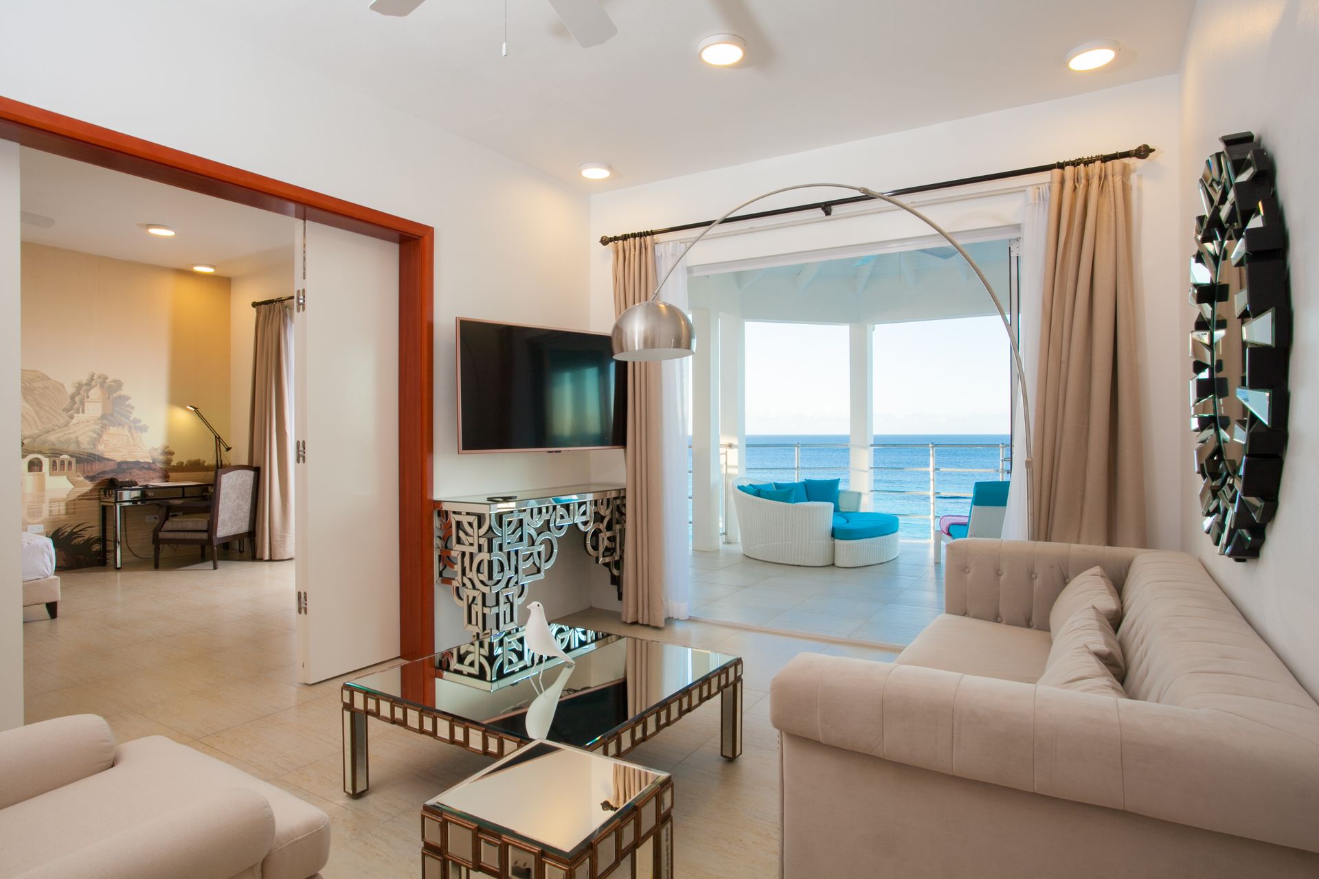 Living room with ocean view, white and tan furniture, large sliding door.