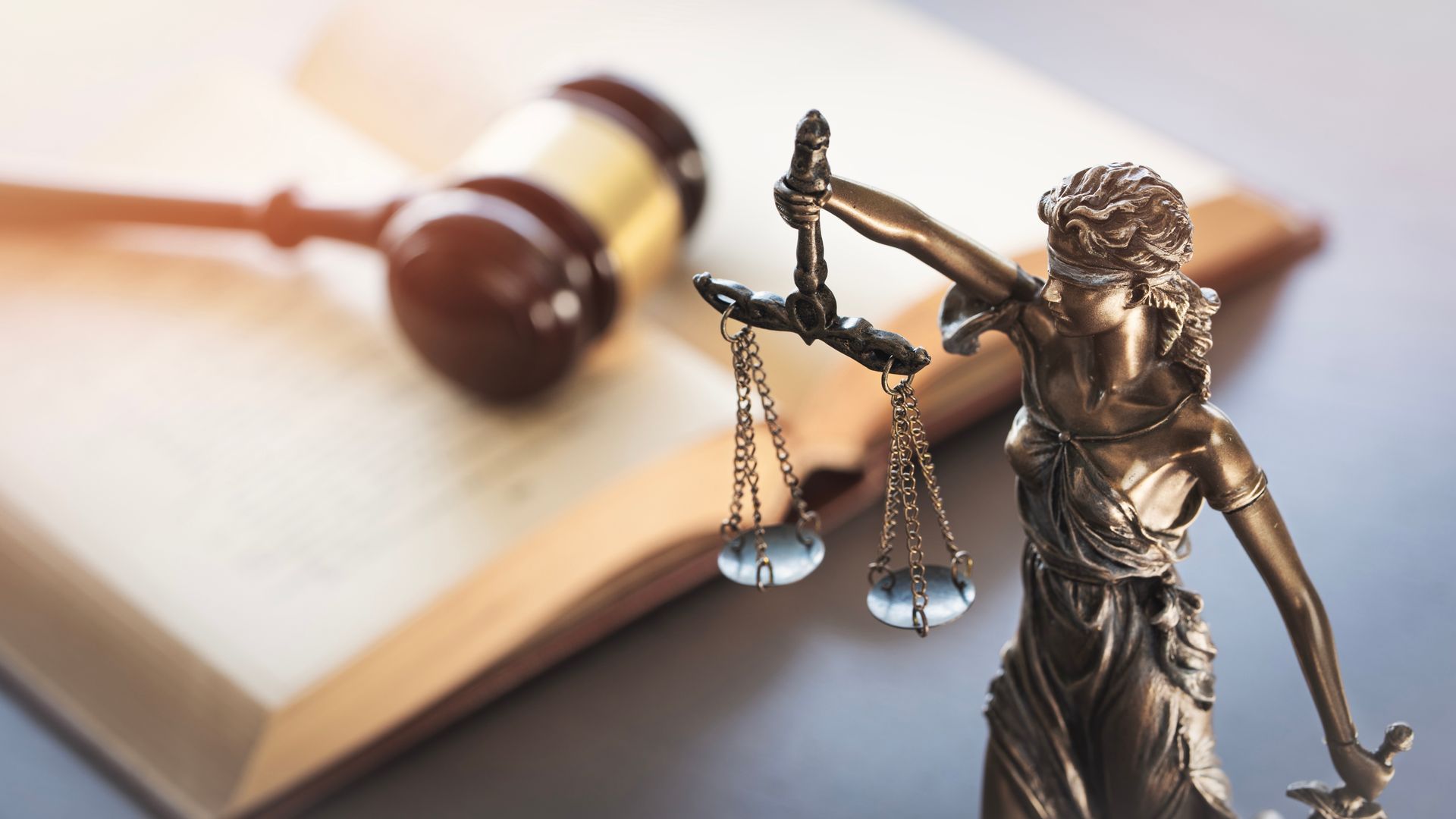Two suited people shaking hands over a gavel in a law office