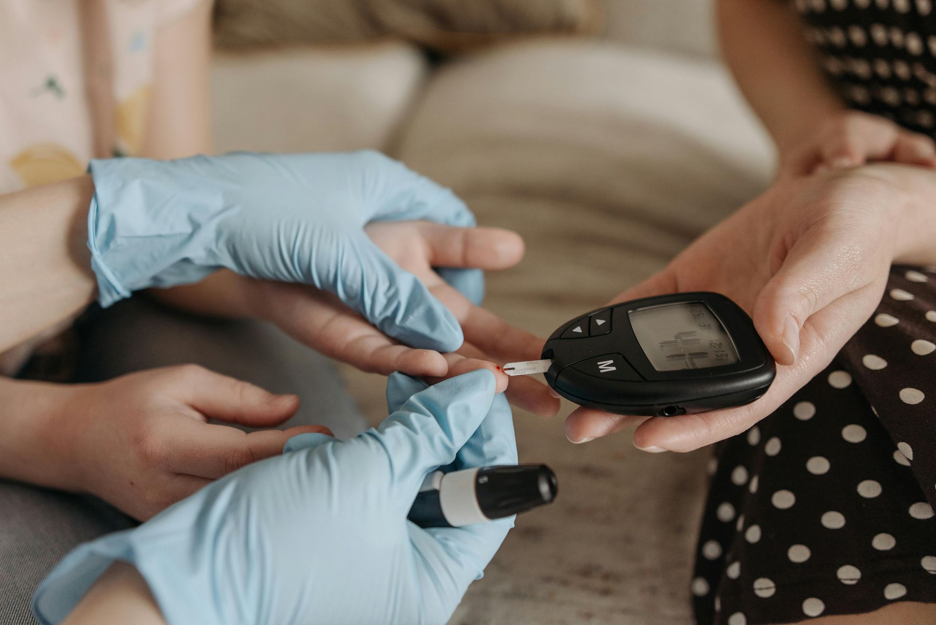 Person testing blood sugar with a glucose meter, with gloved hands.