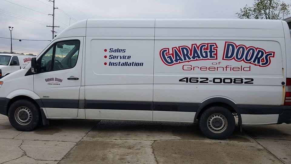 White garage door service van with “Garage Doors Greatfield” logo parked outdoors