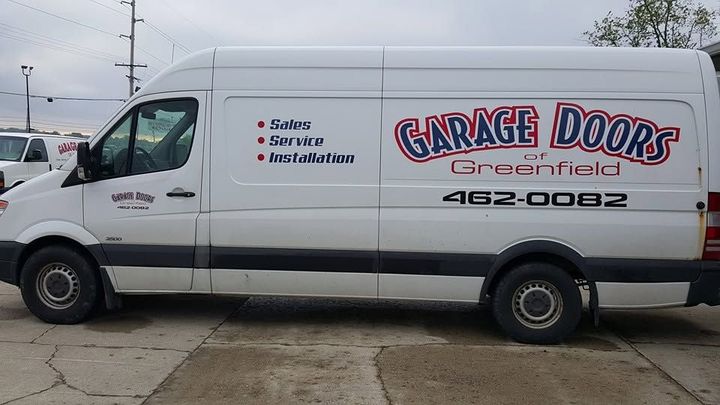 White garage door service van with “Garage Doors Greatfield” logo parked outdoors