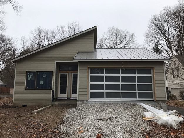 Two-car garage with rustic wood-look doors and a wide concrete driveway