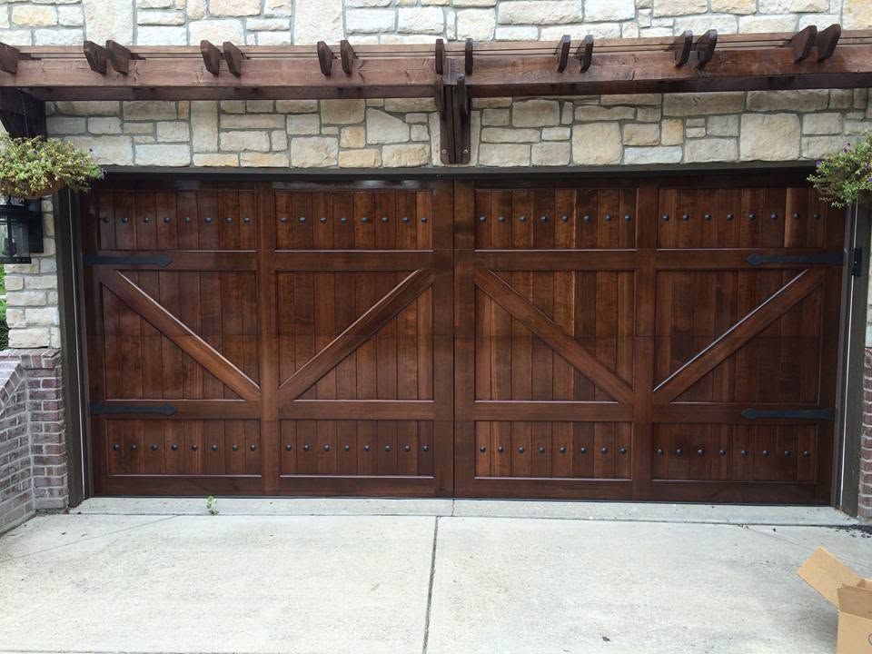 Wooden double garage door with diagonal bracing set in a stone and brick driveway wall