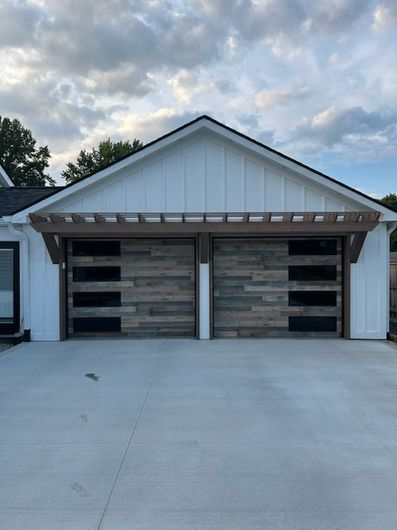 Two-car garage with rustic wood-look doors and a wide concrete driveway