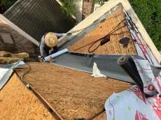 Roofer installing roofing material on a house, working on a sunny day.