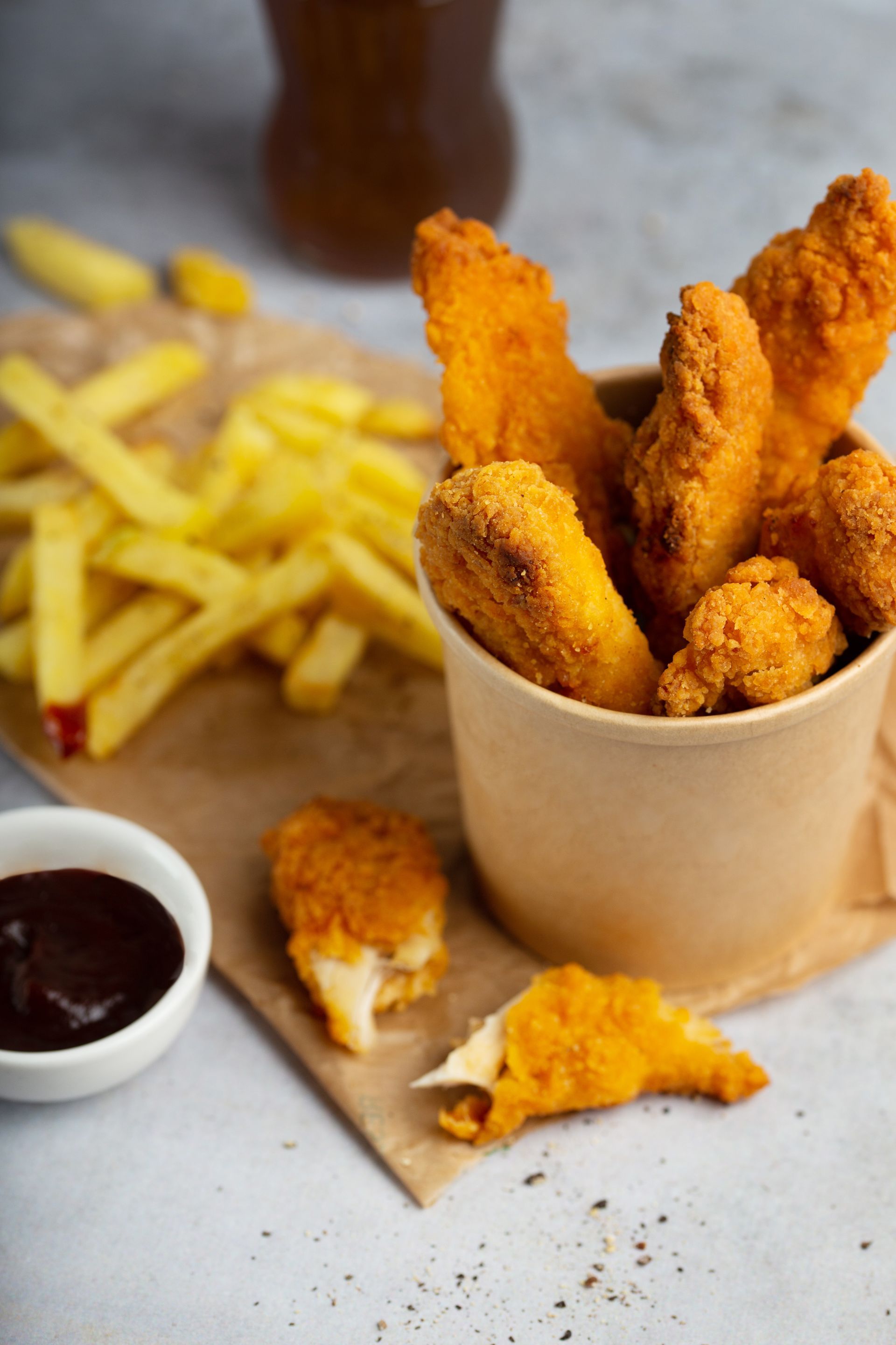 Une tasse de nuggets de poulet et de frites sur une table.