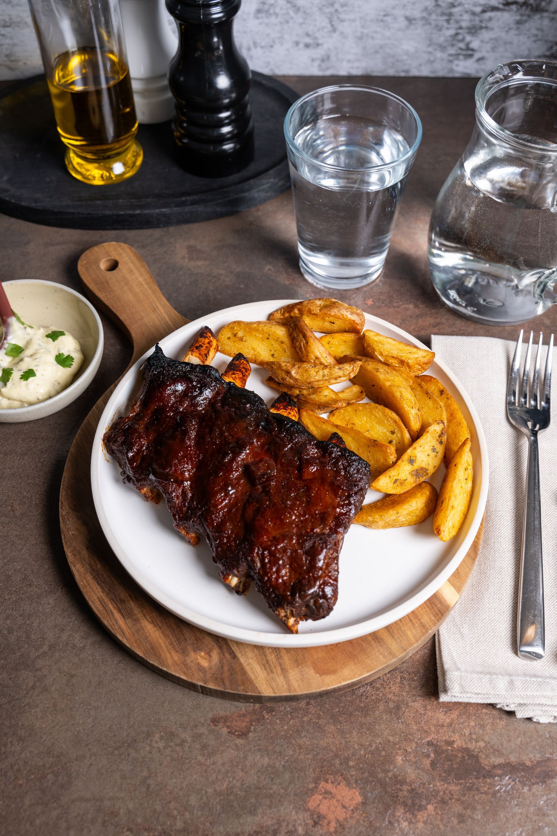 Costillas de cerdo servidas en un plato con patatas al estilo brasserie y steakhouse