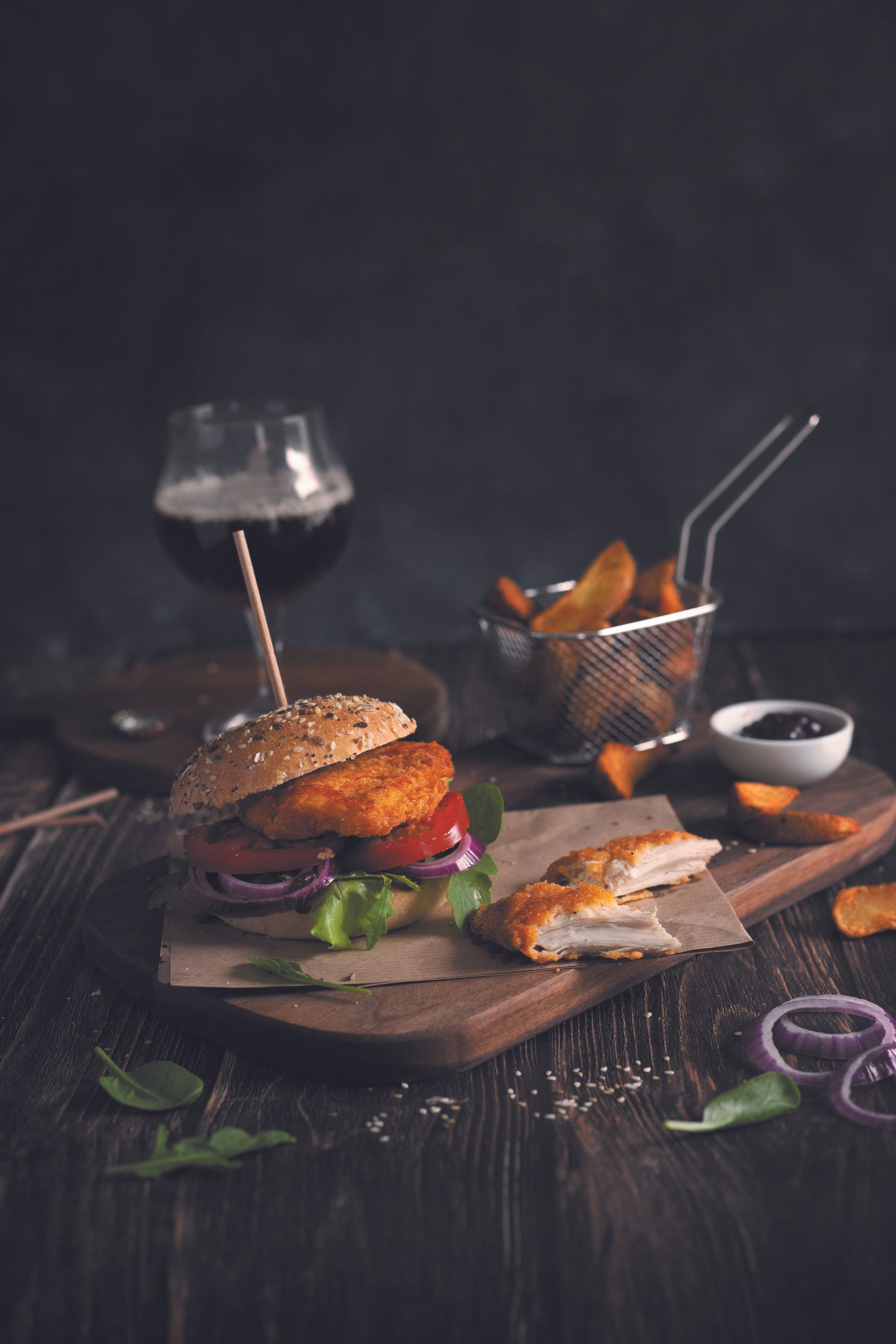 Un hamburger et des frites sur une planche à découper en bois avec un verre de bière.