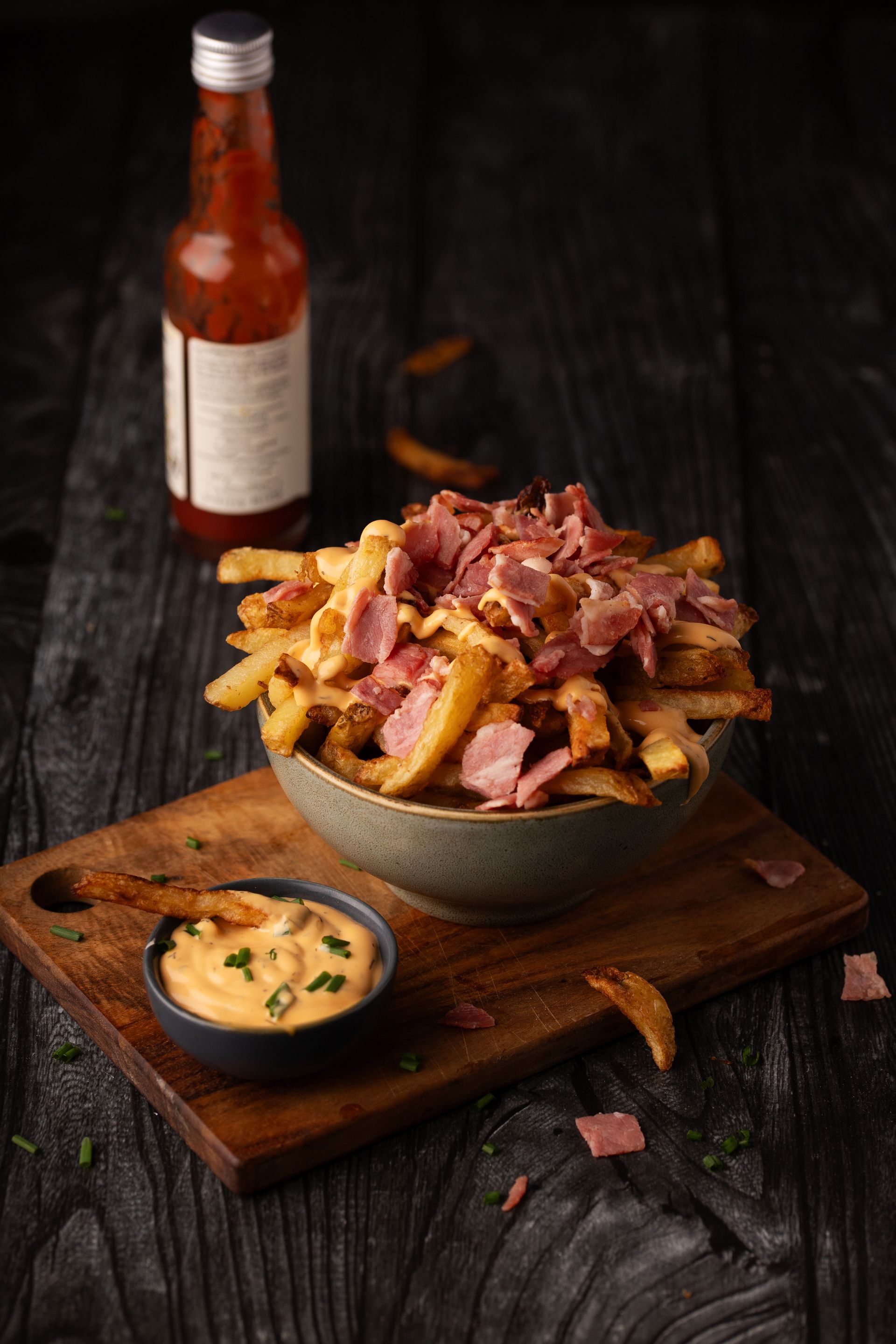 Bol de patatas fritas caseras con trocitos de beicon crujiente y queso cheddar fundido y cremoso.