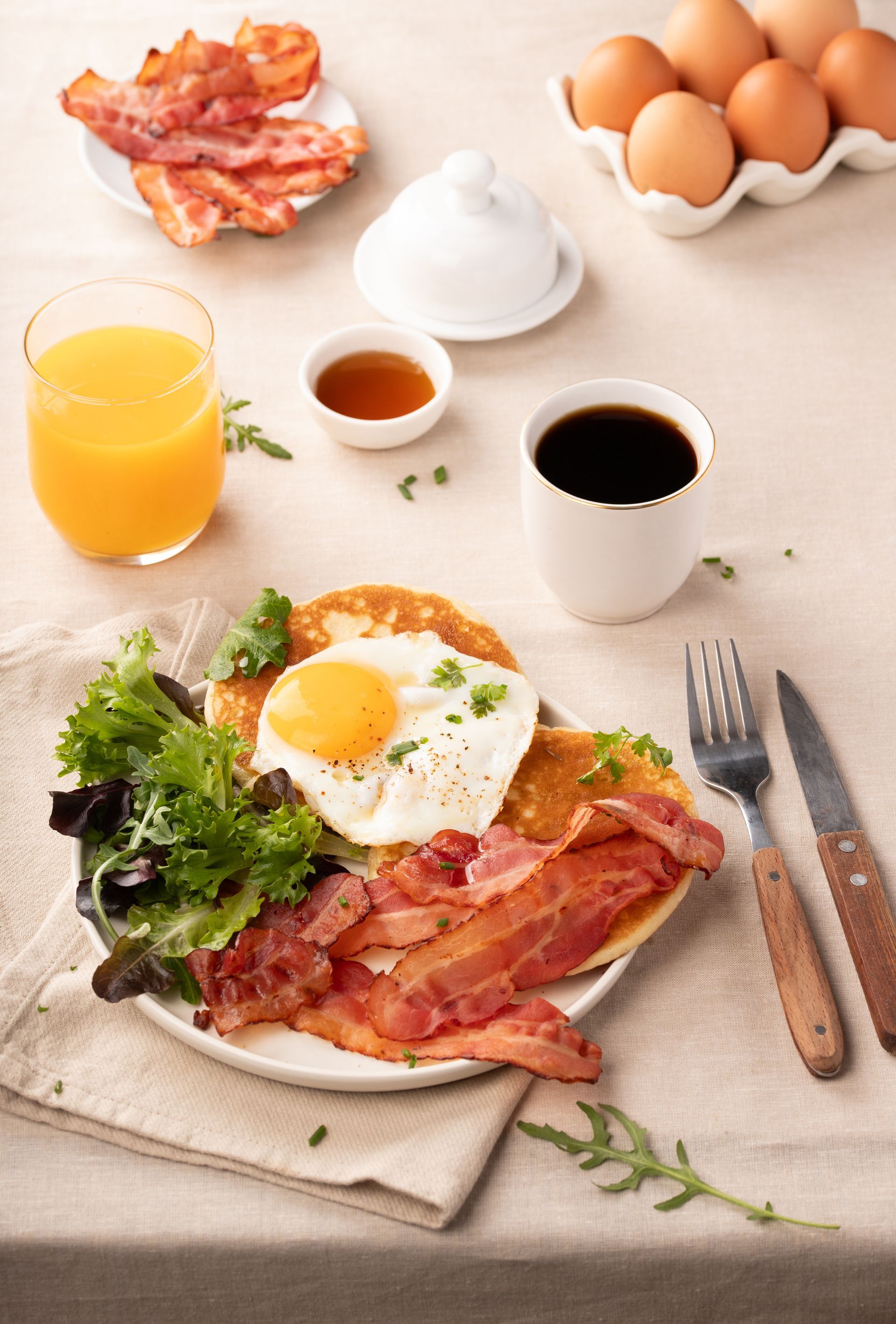 Desayuno con un plato de beicon crujiente y huevo frito, café y zumo de naranja.
